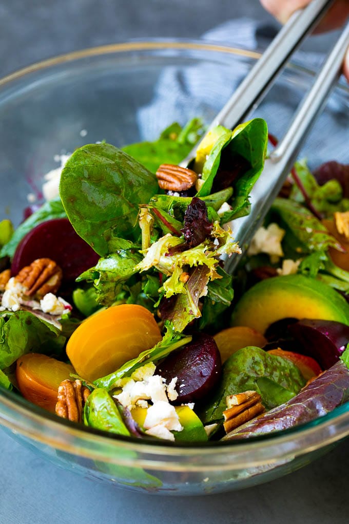 Beet Salad Recipe #beets #avocado #feta #salad #dinner #sraye Tongs serving a portion of beet salad tossed in balsamic dressing.