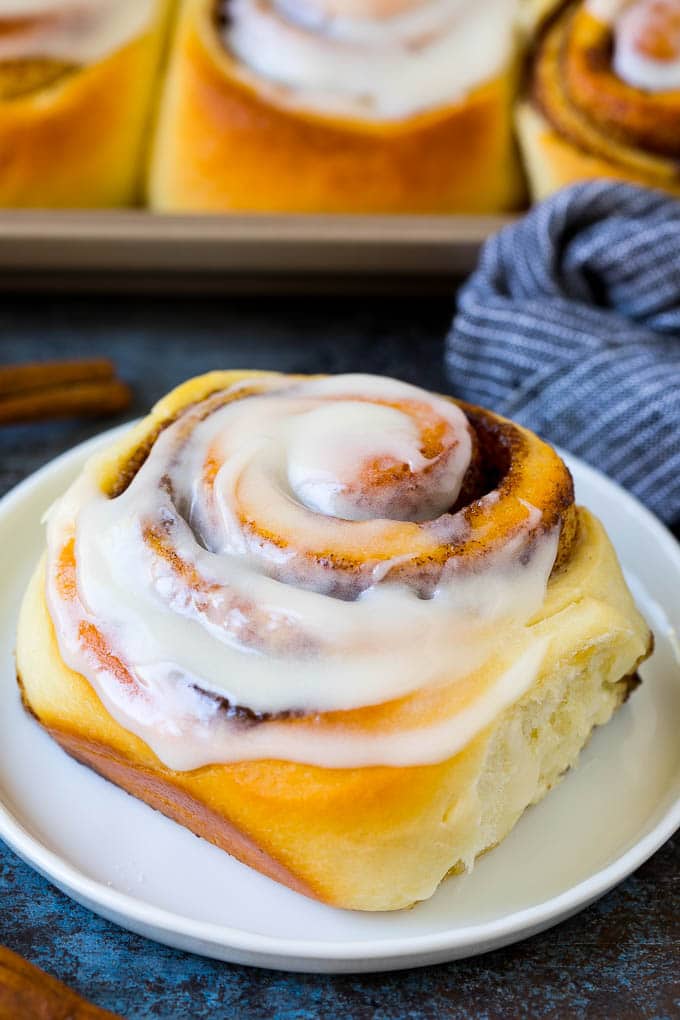 Cinnamon Rolls Recipe | Cinnamon Buns #cinnamon #rolls #pastry #breakfast #brunch #sweets #sraye #baking #bread A frosted cinnamon bun on a serving plate.