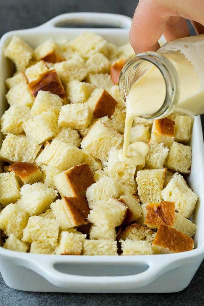 French Toast Casserole Recipe | French Toast Bake #frenchtoast #casserole #breakfast #brunch #sraye #bread A mixture of milk and eggs being poured over cubes of bread.