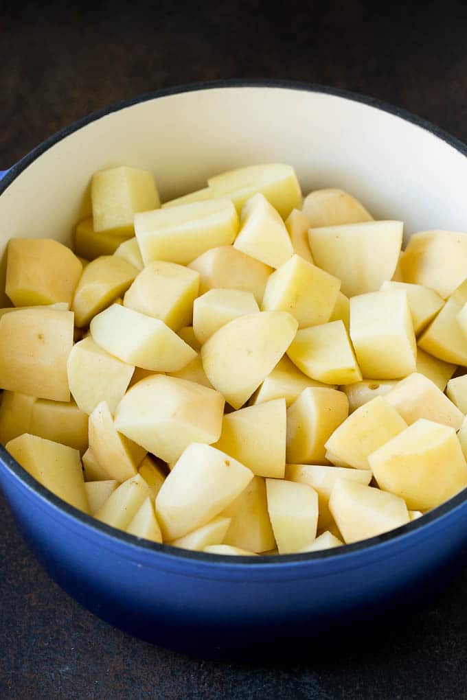 Garlic Mashed Potatoes Recipe #garlic #potatoes #mashedpotatoes #sidedish #dinner #thanksgiving #sraye Diced potatoes in a large blue pot.
