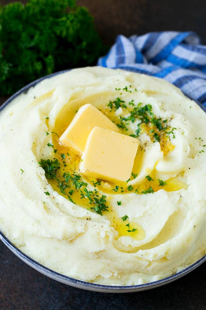 Garlic Mashed Potatoes Recipe #garlic #potatoes #mashedpotatoes #sidedish #dinner #thanksgiving #sraye Garlic mashed potatoes topped with pats of butter and parsley.