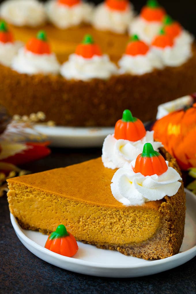 Pumpkin Pie Cheesecake Recipe | Pumpkin Cheesecake #cake #cheesecake #pumpkin #fall #thanksgiving #dessert #sraye A slice of pumpkin pie cheesecake garnished with whipped cream.