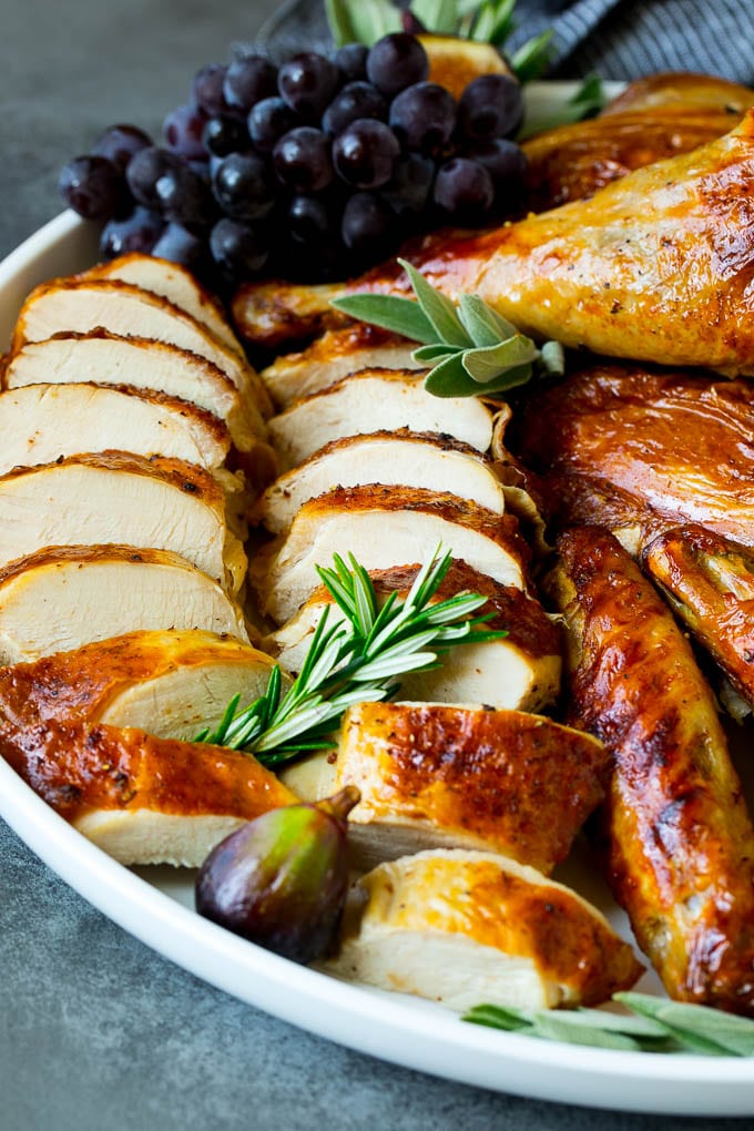Spatchcock Turkey | Roasted Turkey | Thanksgiving Turkey #turkey #thanksgiving #dinner #fall #christmas #sraye Sliced spatchcock turkey on a serving platter garnished with herbs.