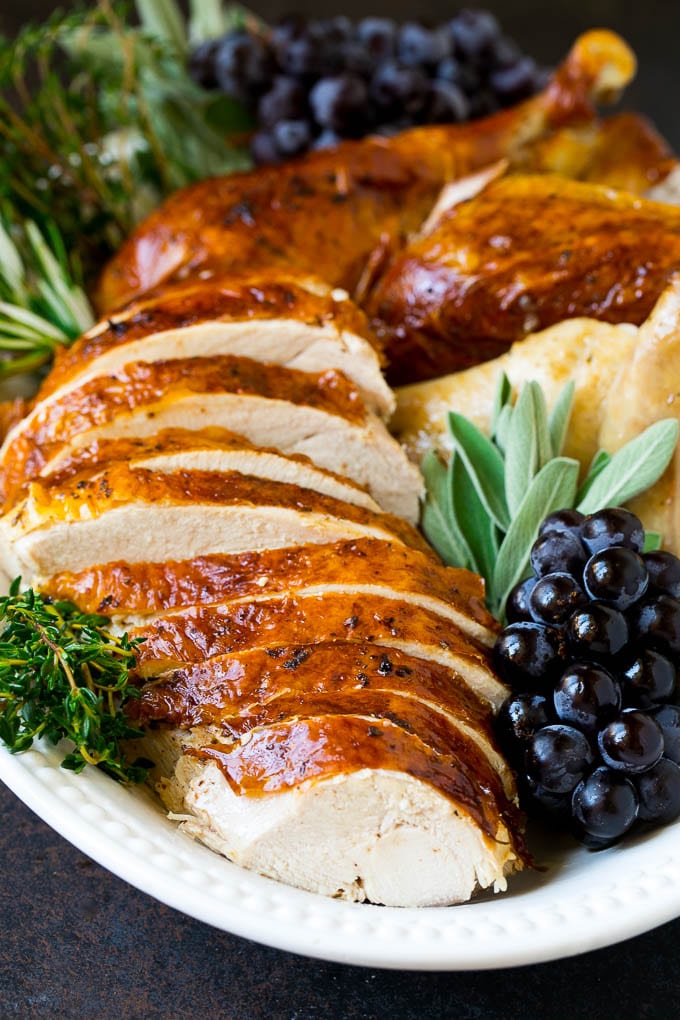 Thanksgiving Turkey Recipe | Roasted Turkey #turkey #thanksgiving #fall #dinner #sraye Sliced Thanksgiving turkey on a serving platter with fresh herbs.