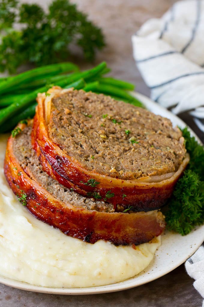 Bacon Wrapped Meatloaf Recipe | Beef Meatloaf #meatloaf #beef #groundbeef #bacon #dinner #sraye Slices of bacon wrapped meatloaf served over mashed potatoes with green beans.