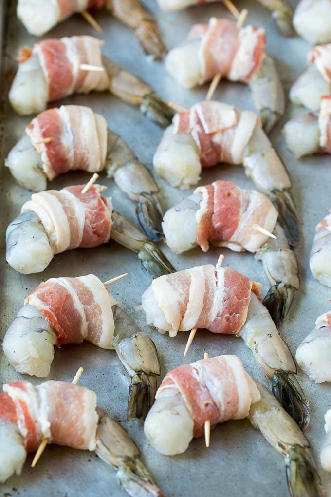 Bacon Wrapped Shrimp Recipe | Bacon Shrimp #shrimp #bacon #appetizer #dinner #sraye #seafood Raw seafood on a sheet pan wrapped in pork.