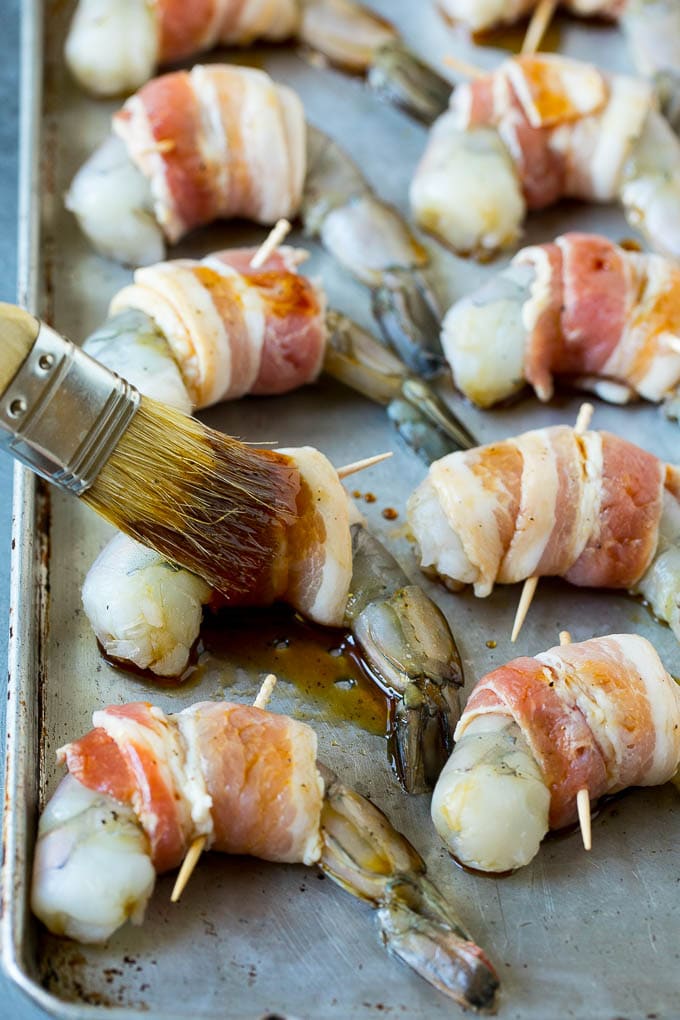 Bacon Wrapped Shrimp Recipe | Bacon Shrimp #shrimp #bacon #appetizer #dinner #sraye #seafood A basting brush applying sauce to shrimp.