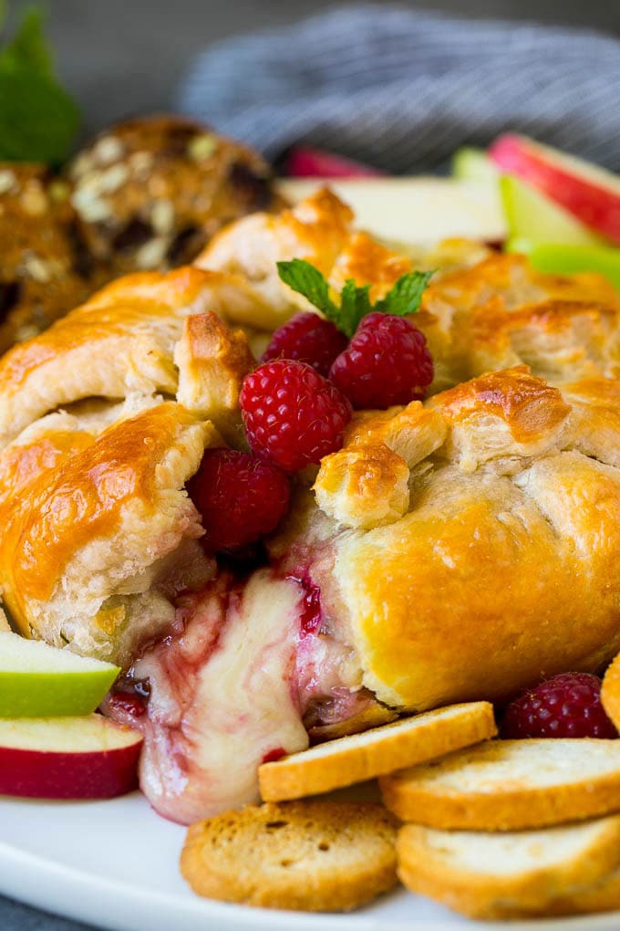 Baked Brie Recipe | Pastry Wrapped Brie #brie #cheese #appetizer #pecans #raspberries #sraye Baked brie cut open with cheese spilling out.
