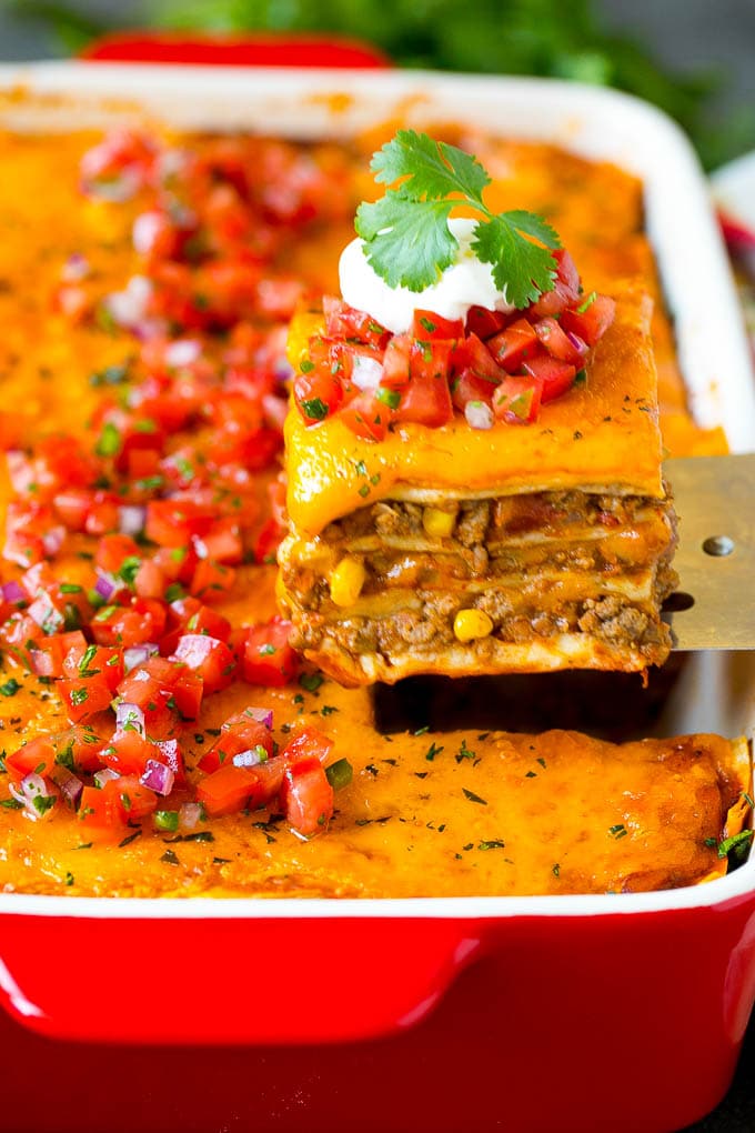 Mexican Lasagna Recipe | Mexican Casserole #mexican #lasagna #groundbeef #beans #dinner #cheese #sraye A spatula serving up a portion of Mexican lasagna.