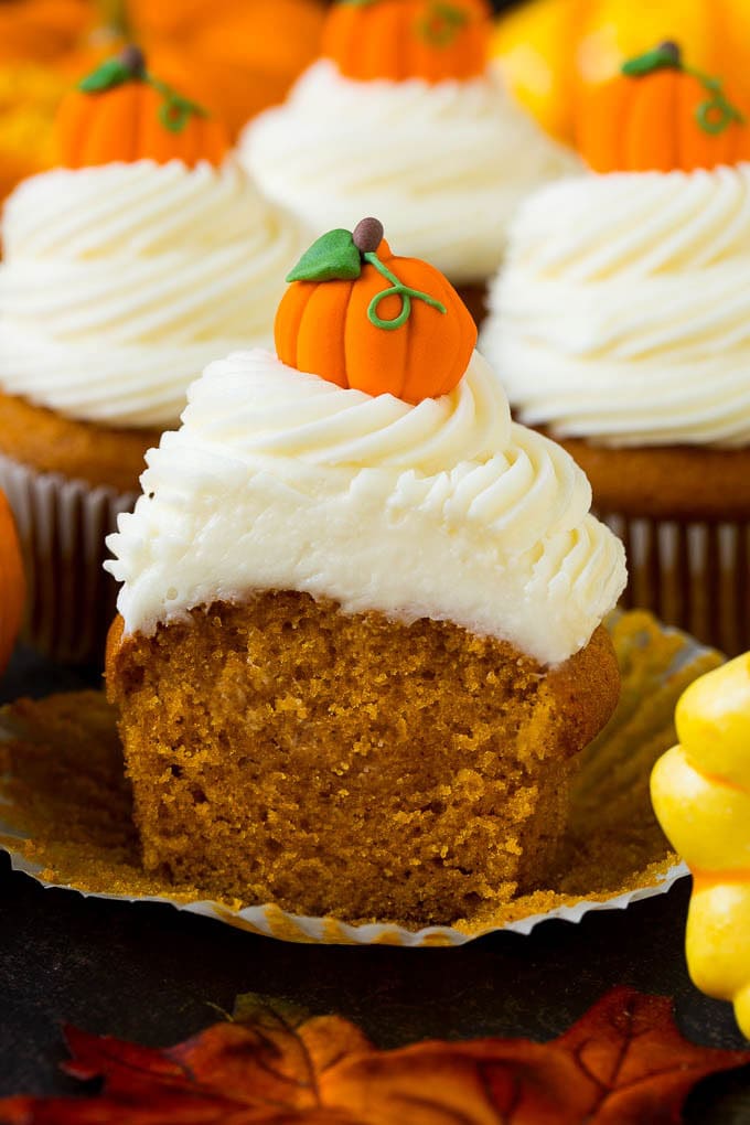 Pumpkin Cupcakes Recipe | Pumpkin Cake #cake #cupcakes #pumpkin #frosting #baking #fall #thanksgiving #sraye A pumpkin cupcake cut in half, surrounded by fall decorations.