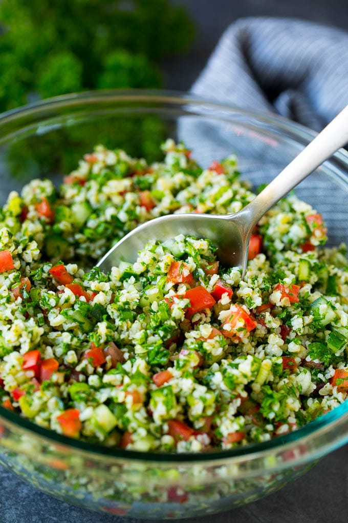Tabbouleh Salad | Tabouli #salad #wheat #tomatoes #cucumber #healthy #sidedish #dinner #sraye A bowl of tabbouleh with a serving spoon in it.