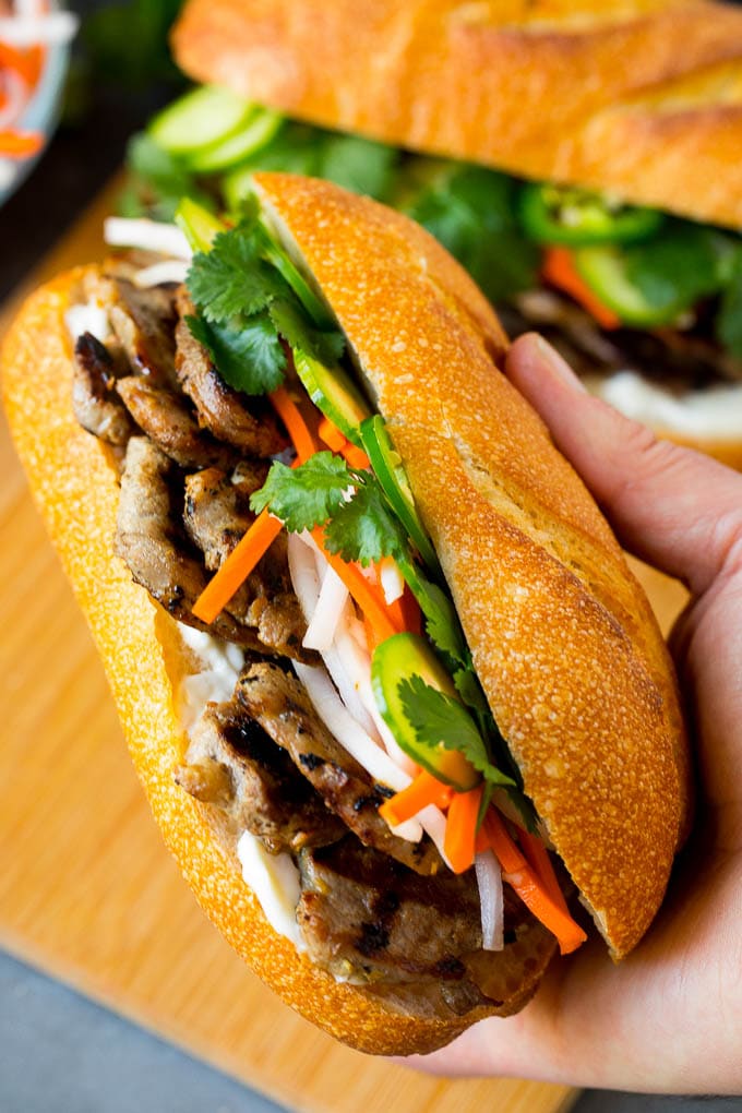 Bahn Mi Sandwich Recipe #sandwich #pork #lunch #dinner #sraye A hand holding a pork banh mi sandwich.
