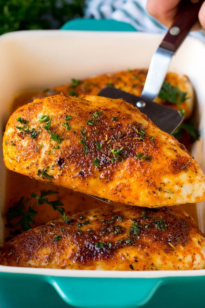 Baked Chicken Breast Recipe #chicken #dinner #sraye A spatula serving up a portion of roasted chicken breast.