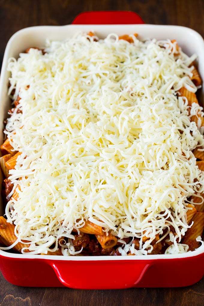 Baked Rigatoni Pasta #pasta #dinner #italianfood #groundbeef #sraye #casserole A pan of pasta in sauce topped with shredded cheese.