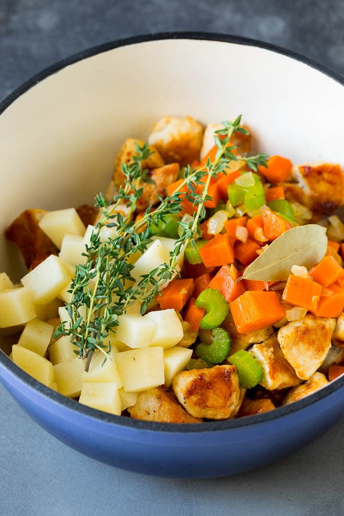 Chicken Pot Pie Soup Recipe | Chicken Soup #soup #chicken #dinner #comfortfood #sraye Ingredients such as vegetables, potatoes and herbs in a pot.