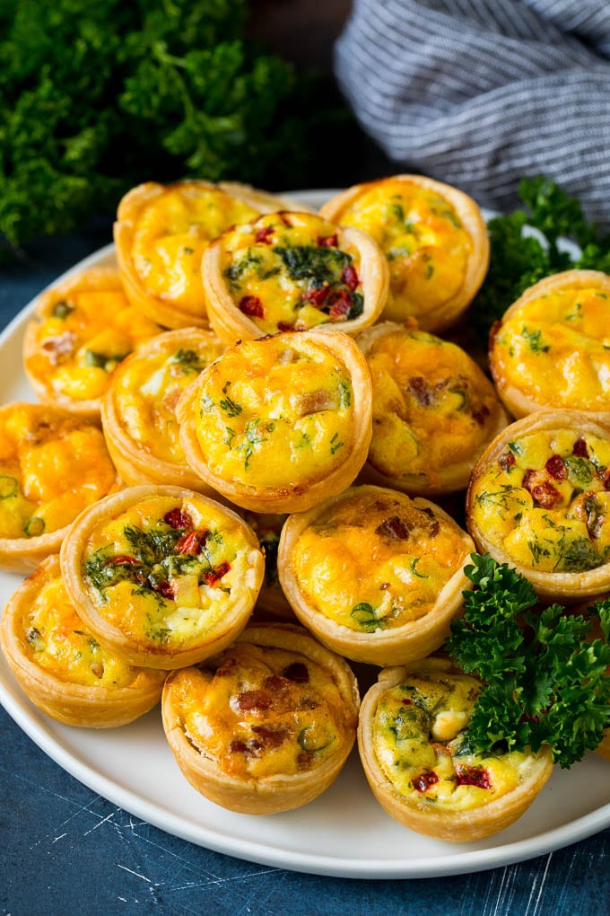 Mini Quiche Recipe #eggs #breakfast #brunch #appetizer #sraye A plate of mini quiche filled with meats, vegetables and cheeses.