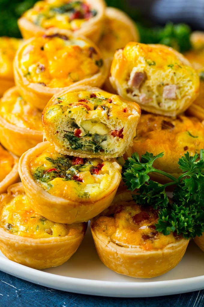 Mini Quiche Recipe #eggs #breakfast #brunch #appetizer #sraye A serving platter of mini quiche with some cut in half.