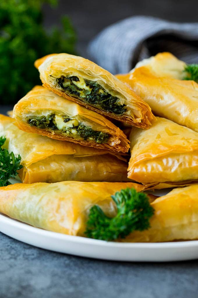 Spanakopita Recipe #appetizer #snack #spinach #cheese #sraye A plate of spanakopita with two cut in half.