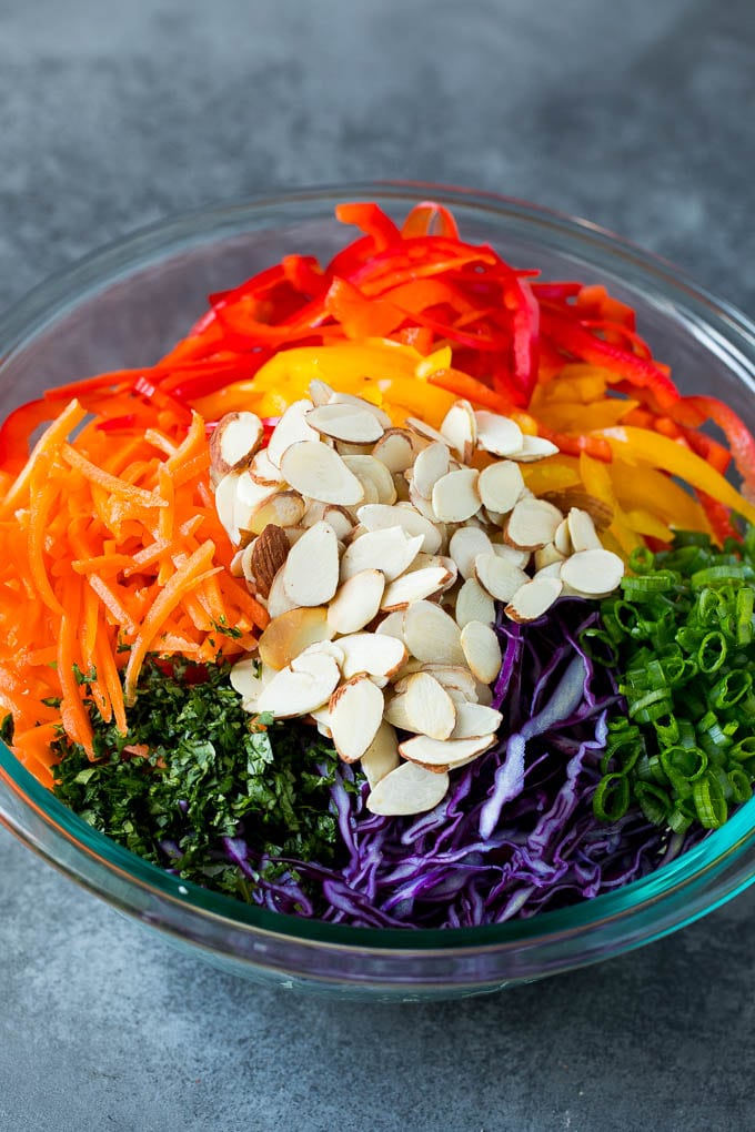 Asian Slaw Recipe #salad #slaw #sidedish #sraye Shredded cabbage, vegetables and almonds in a bowl.