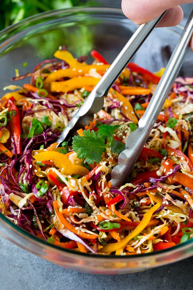 Asian Slaw Recipe #salad #slaw #sidedish #sraye Tongs serving up a portion of Asian slaw.