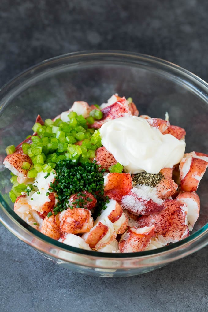 Lobster rolls stuffed with creamy lobster salad in a toasted bun. #lobster #sraye Lobster, chives, celery and mayonnaise in a bowl.