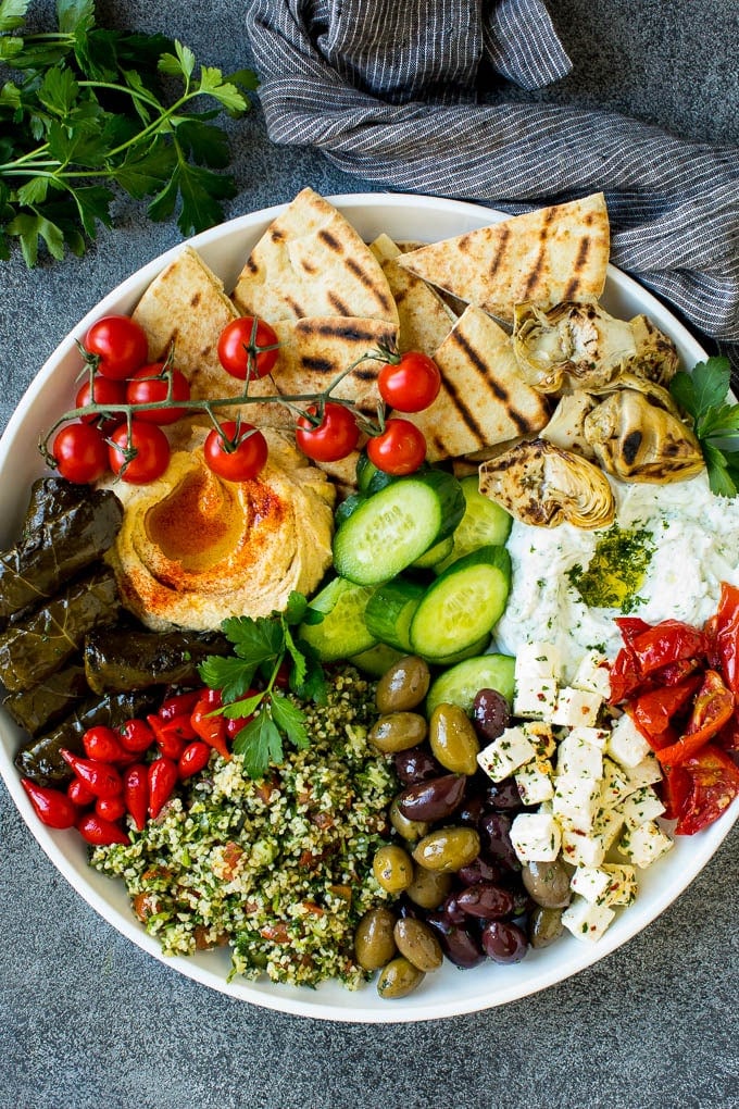 This mezze platter is filled with Mediterranean delicacies including dolmas, hummus, vegetables, pita bread and salads. #appetizer #sraye A mezze platter filled with dips, pita bread, vegetables, olives and cheese.