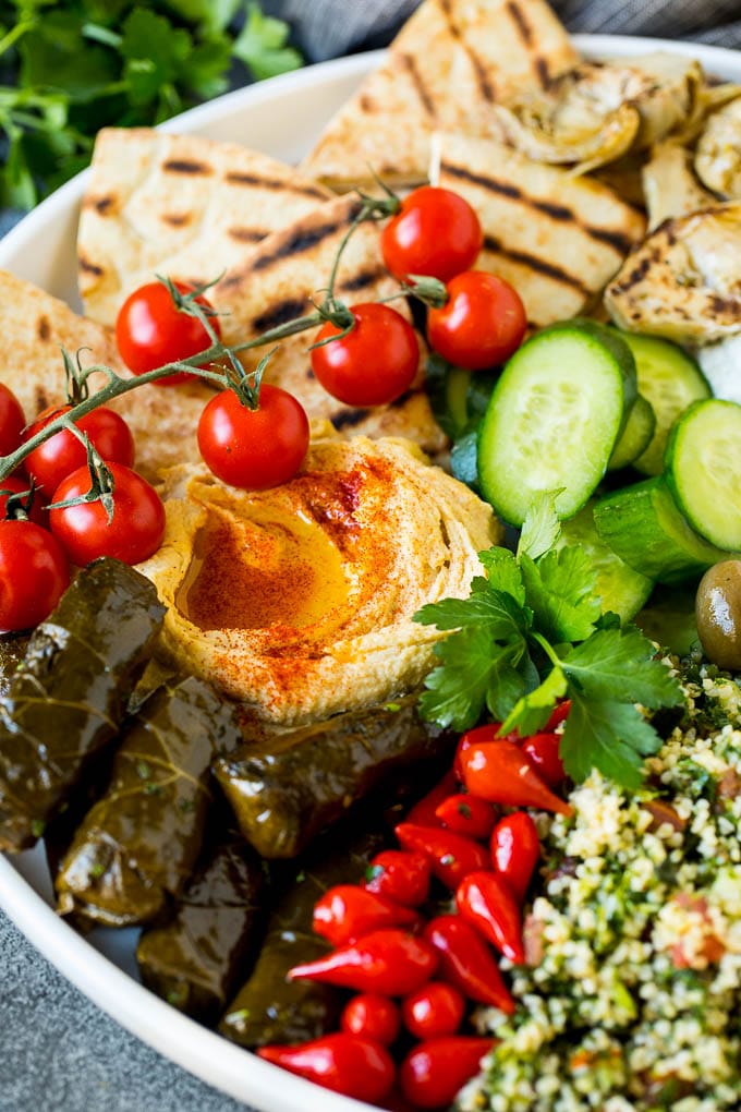 This mezze platter is filled with Mediterranean delicacies including dolmas, hummus, vegetables, pita bread and salads. #appetizer #sraye A Mediterranean mezze platter with hummus, dolmas and vegetables.