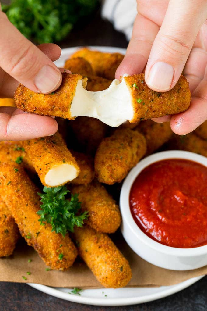 Mozzarella Sticks Recipe #cheese #appetizer #sraye A hand pulling apart mozzarella sticks.