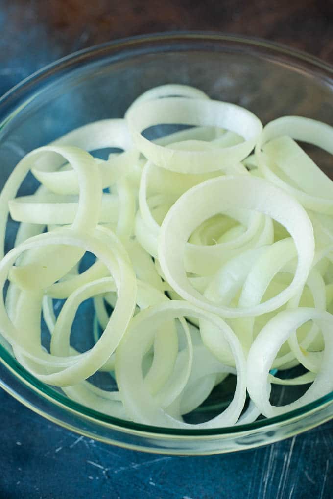 Crispy homemade onion rings that are fried in a flavorful beer batter. #onions #sraye #appetizer Raw onion slices in a bowl.