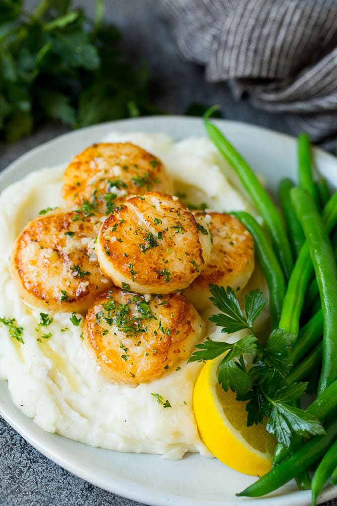 Seared scallops with a garlic and herb butter sauce. An easy and elegant dinner! #seafood #dinner #sraye Seared scallops served with mashed potatoes and green beans.