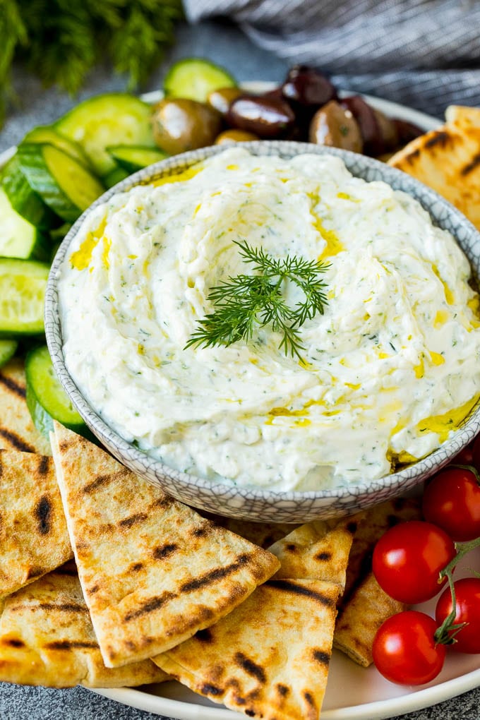 The best homemade tzatziki sauce with cucumber and herbs mixed into Greek yogurt. #appetizer #sraye A bowl of tzatziki served with pita bread and vegetables.