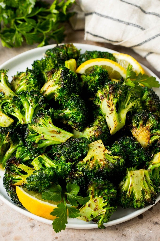 Grilled broccoli is packed with flavor and is a colorful and healthy side dish! #broccoli #sraye Grilled broccoli topped with parsley and garnished with lemon wedges.