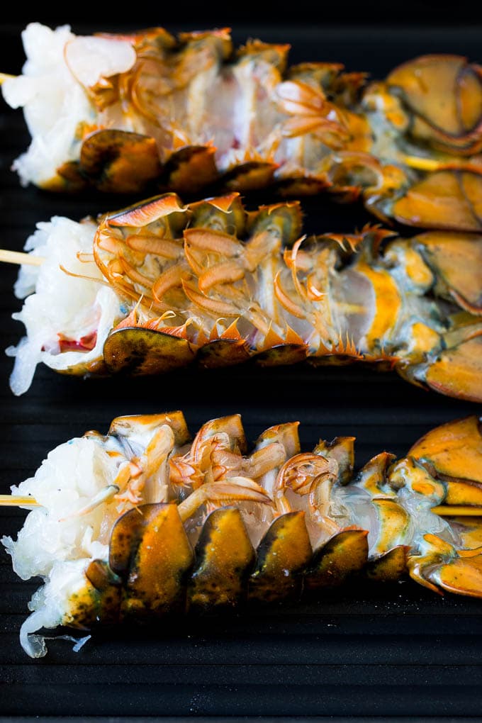 Grilled lobster tail drizzled with garlic butter is an easy and elegant dinner option. #lobster #sraye Lobster tails upside down on a grill pan.