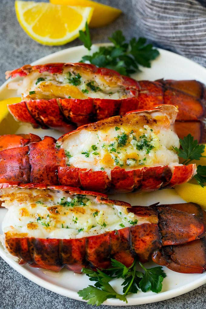 Grilled lobster tail drizzled with garlic butter is an easy and elegant dinner option. #lobster #sraye Grilled lobster tail topped with garlic butter and garnished with lemon and parsley.