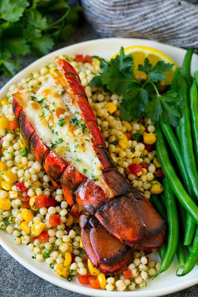 Grilled lobster tail drizzled with garlic butter is an easy and elegant dinner option. #lobster #sraye Grilled lobster tail served with couscous and green beans.
