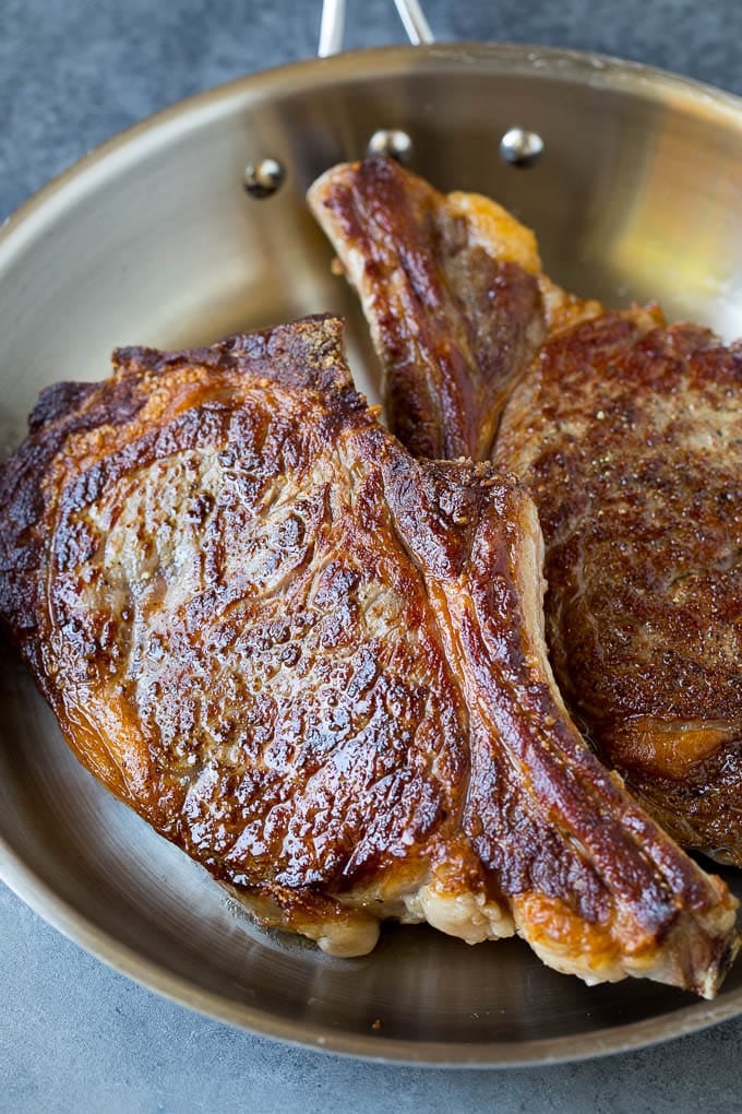 This rib eye steak recipe is tender and juicy beef seared to golden brown perfection, and topped with garlic butter and herbs. A simple steak preparation that tastes like it came from a fancy restaurant! Seared steaks in a skillet.
