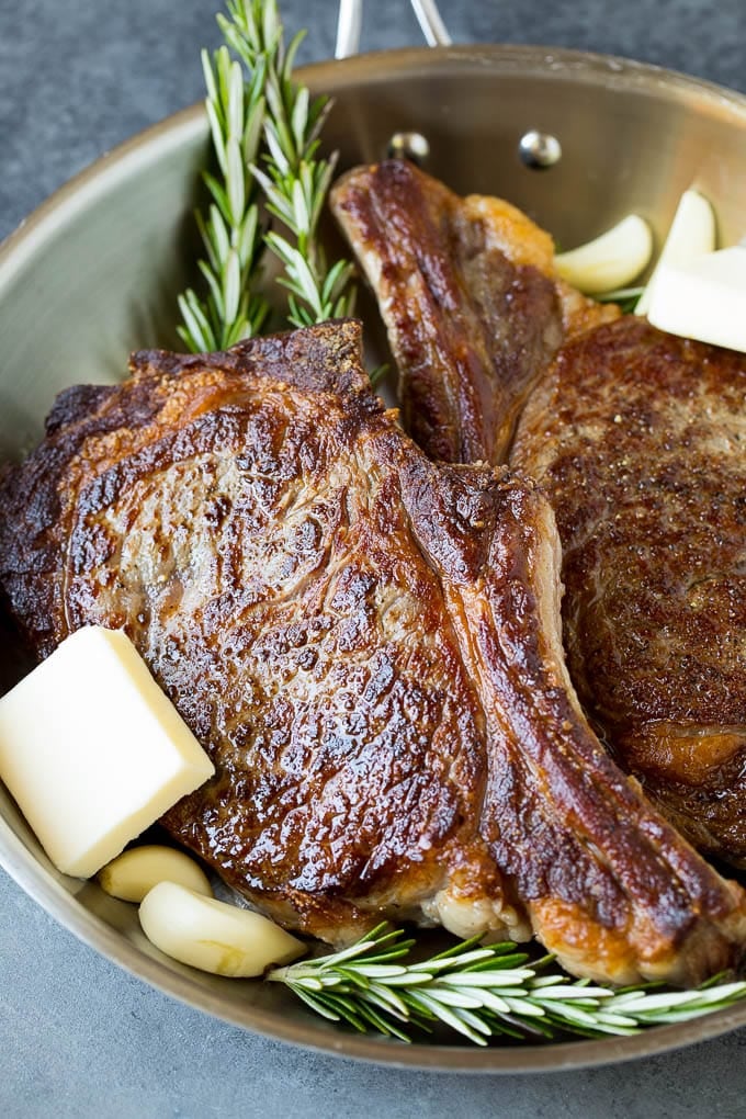 This rib eye steak recipe is tender and juicy beef seared to golden brown perfection, and topped with garlic butter and herbs. A simple steak preparation that tastes like it came from a fancy restaurant! Steak with garlic, butter and rosemary sprigs.
