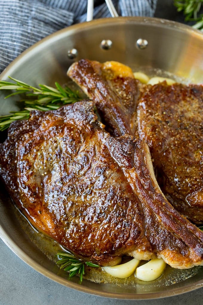 This rib eye steak recipe is tender and juicy beef seared to golden brown perfection, and topped with garlic butter and herbs. A simple steak preparation that tastes like it came from a fancy restaurant! Rib eye steak with garlic butter and rosemary in a skillet.