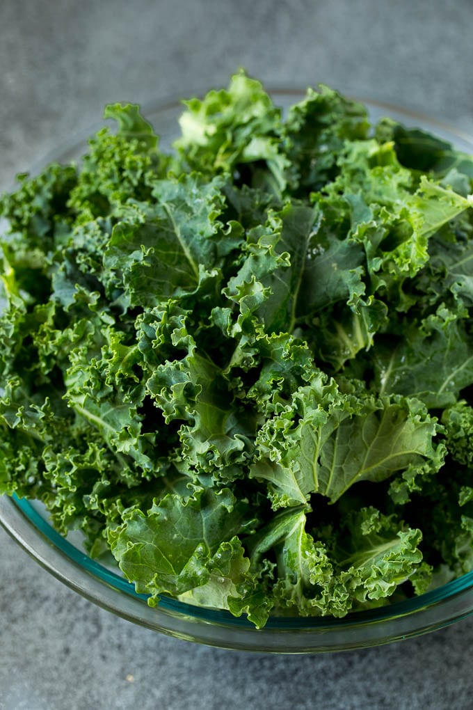 Sauteed kale flavored with olive oil and garlic, a quick and easy side dish! #kale #sraye Chopped kale in a mixing bowl.
