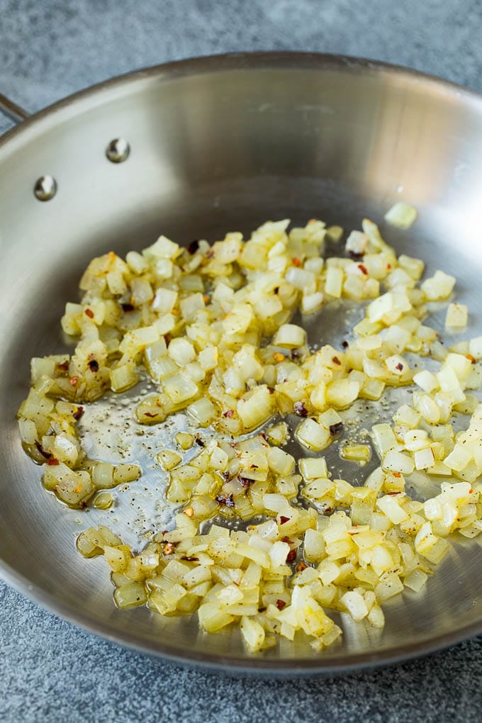 Sauteed kale flavored with olive oil and garlic, a quick and easy side dish! #kale #sraye Sauteed onions in a skillet.