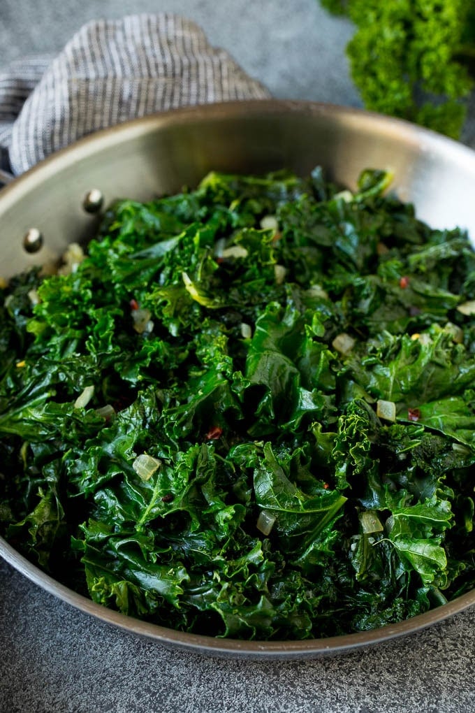 Sauteed kale flavored with olive oil and garlic, a quick and easy side dish! #kale #sraye Cooked kale with olive oil, onions and garlic.