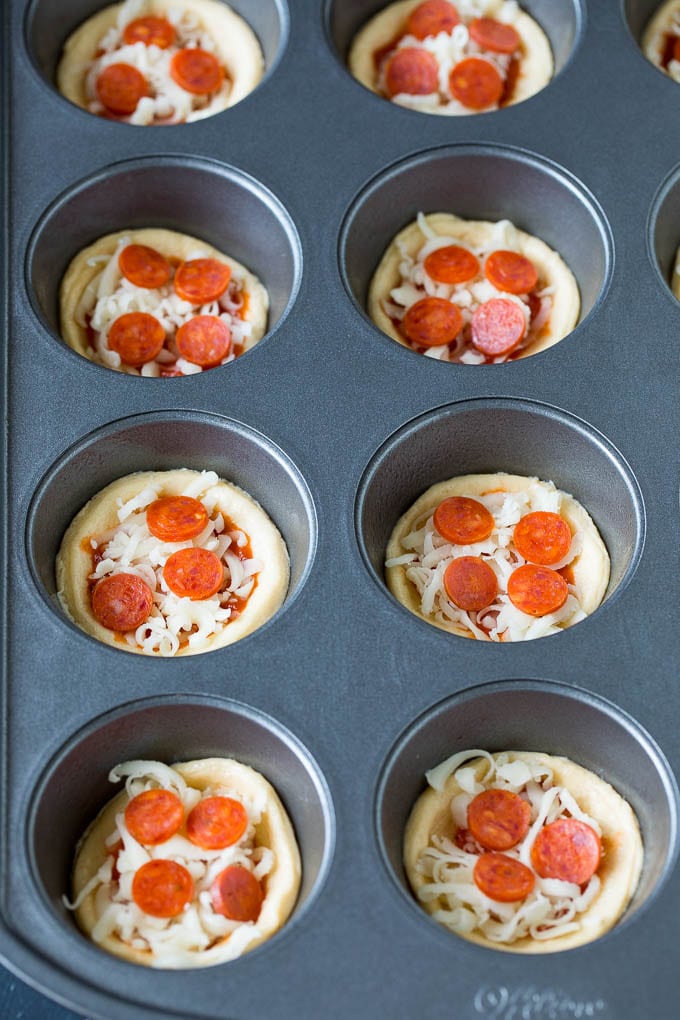 Mini pizzas topped with pepperoni are a fun and easy appetizer option. #pizza #sraye #appetizer Dough topped with sauce, cheese and mini pepperoni.