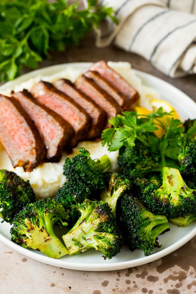 Grilled broccoli is packed with flavor and is a colorful and healthy side dish! #broccoli #sraye Grilled broccoli on a plate with steak and mashed potatoes.