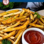 A plate of baked french fries which are potato strips coated in oil and seasonings, then oven baked until golden brown and crispy.